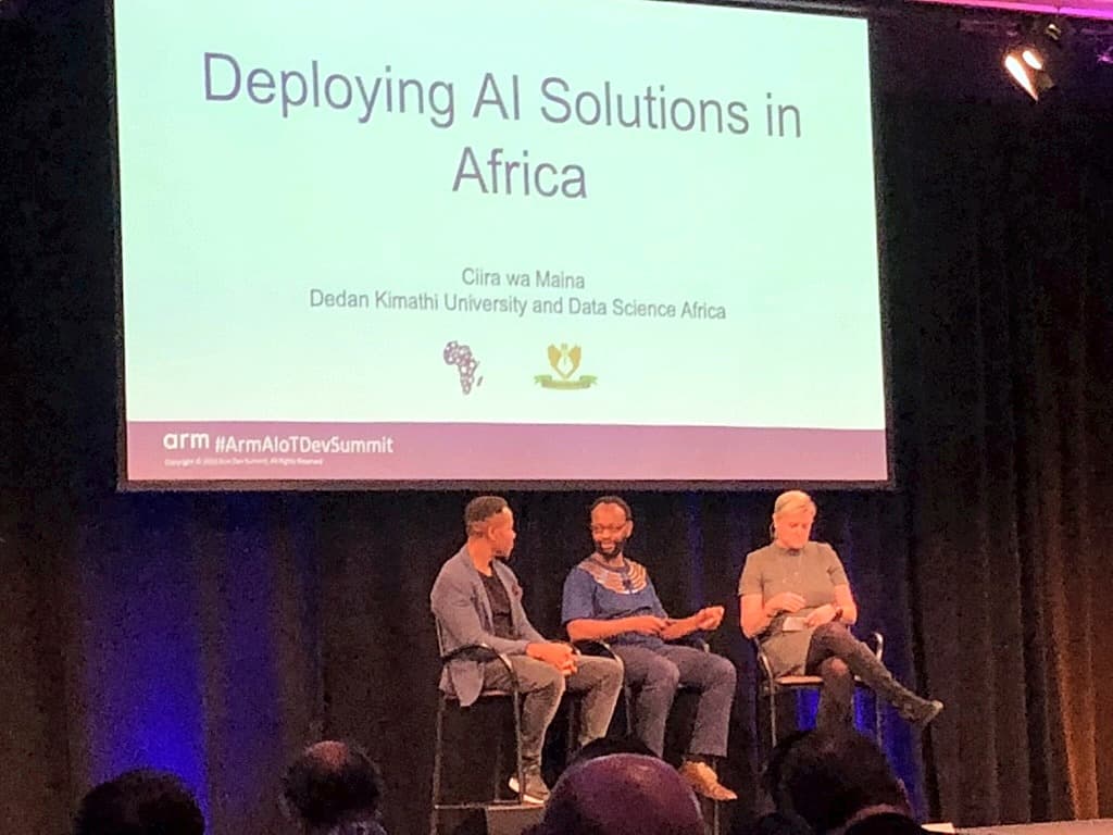 A three-person panel on stage beneath a slide reading "Deploying AI Solutions in Africa" by Ciira wa Maina of Dedan Kimathi University and Data Science Africa