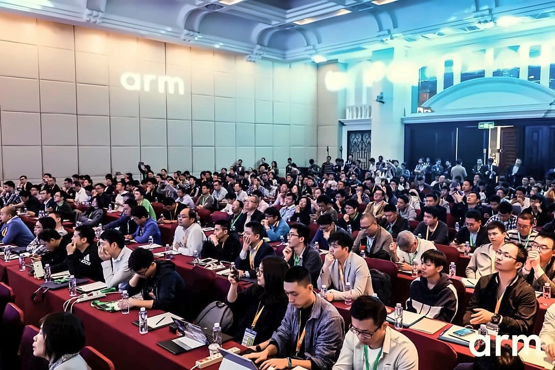 A packed ballroom of several hundred seated developers facing the stage, with the Arm logo projected on the wall