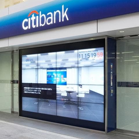 The Citibank branch exterior at night with the illuminated storefront and display screens visible from the street