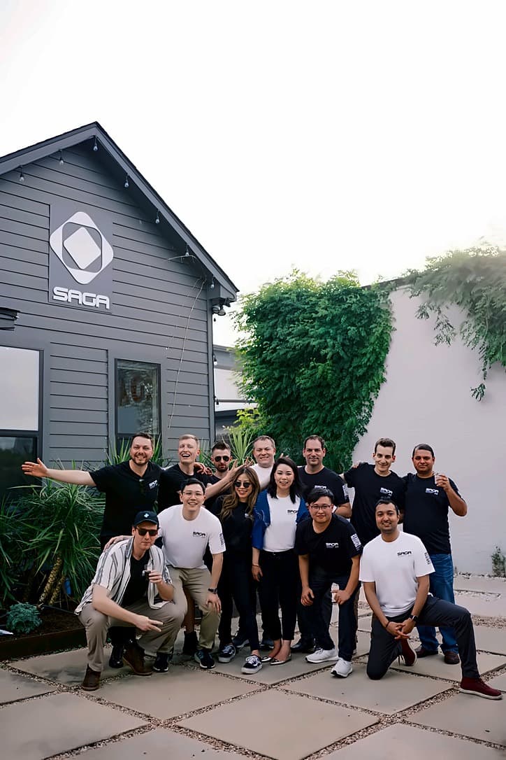 The Saga team outside the Multiverse Reactor house in Austin, under the Saga sign mounted on the gable