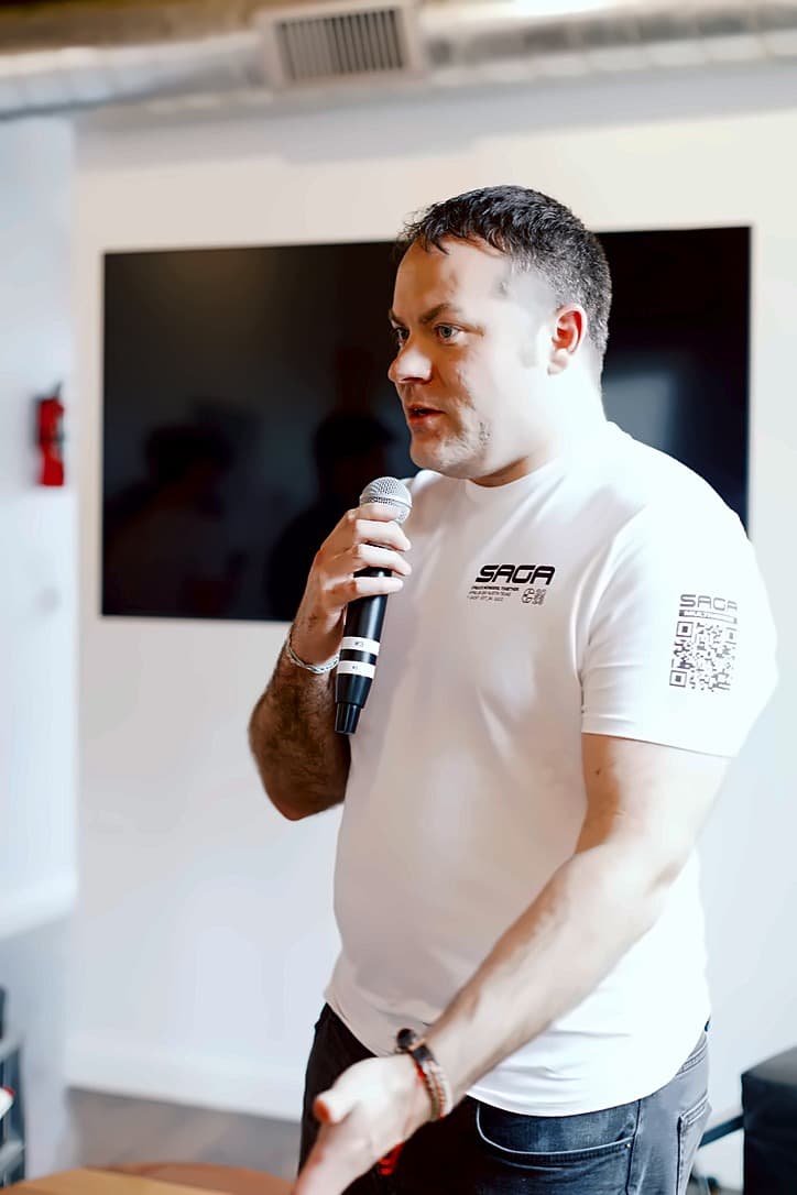 A speaker addressing the room, wearing a Multiverse Reactor shirt
